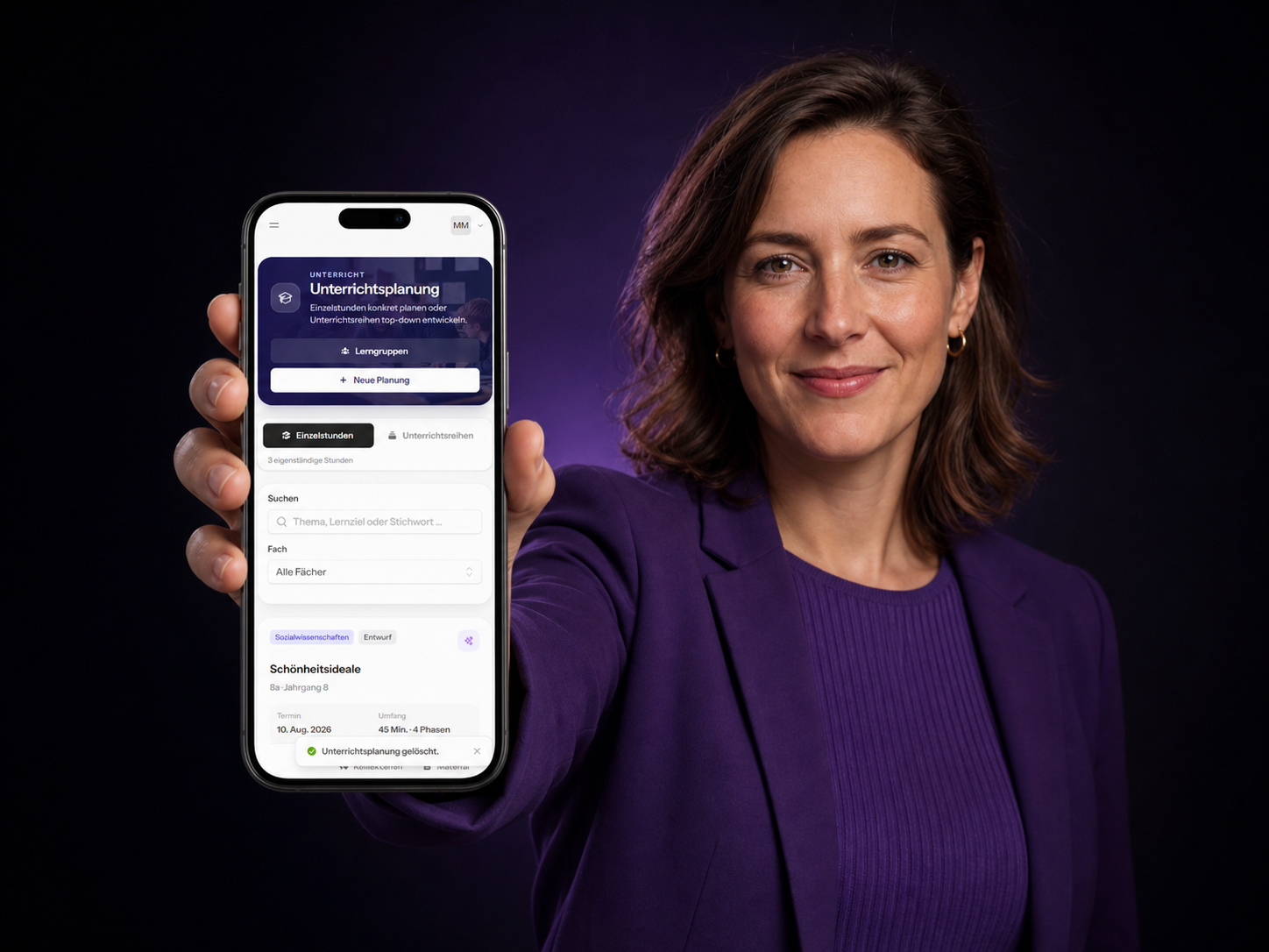 Eine Lehrerin in violetter Kleidung hält ein Smartphone mit der Unterrichtsplanung von Tafelzauber nach vorn.